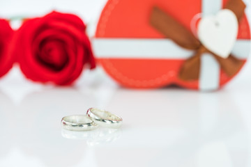 Wedding ring and heart-shaped box on white