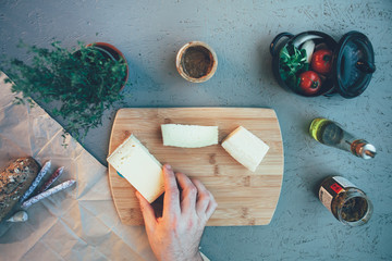 high angle view of and hand picking up cheese from a chopping board and ingredients around the table - Powered by Adobe
