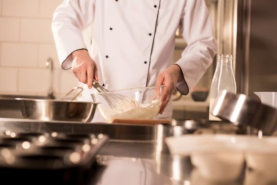 partial view of confectioner with whisk making dough in restaurant kitchen