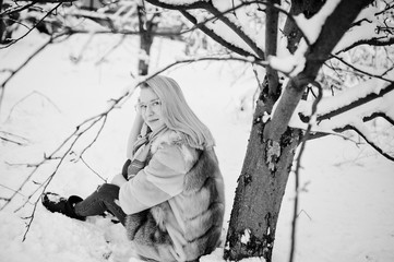 Fototapeta na wymiar Portraiy of blonde girl in glasses, red fur coat and scarf at winter day.