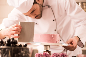 focused confectioner making sweet cake in restaurant kitchen