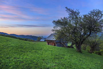 Rural farm with old wooden hut at sunset near Bran, Transylvania
