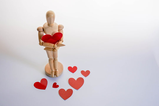 Red heart paper is in the embrace of mannaquin, Surrounded by red heart paper scattered on a white background. The happiness and love surrounds human beings as well.