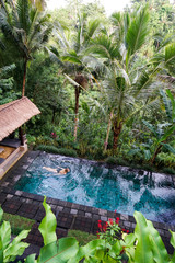 A young girl is floating in the infinity pool in the jungle. Taken on the island of Bali in Ubud.