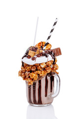 Chocolate indulgent extreme milkshake with chocolate, popcorn and sweets. Crazy freakshake food...