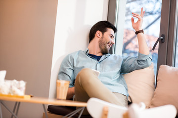 cheerful man looking out window in coffee shop