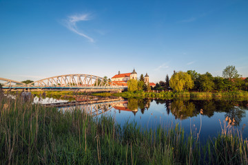 Obraz premium View at bridge over the Narew river and baroque Church of the Holy Trinity in Tykocin town, Podlasie, Poland