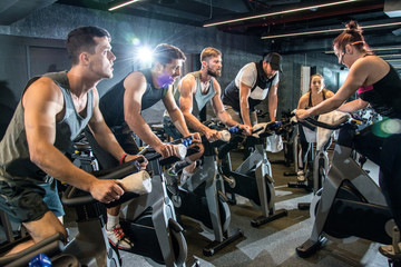 Group of sporty people having spinning class at gym.