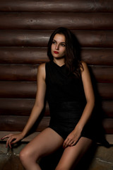Stylish brunette model in black shirt posing at the wood background