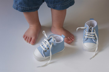 the first baby shoes on the background of the  babies feet 