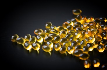 Capsules of fish oil in gold cup on black