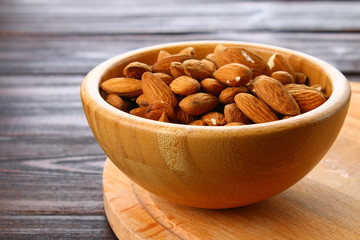 Raw dry nuts of almonds in a wooden bowl on a wooden table.