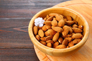 Raw dry nuts of almonds in a wooden bowl on a wooden table.
