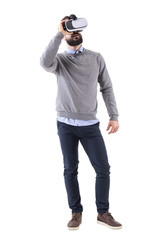 Fototapeta premium Young smart casual guy enjoying virtual reality glasses experience looking up. Full body length portrait isolated on white studio background. 