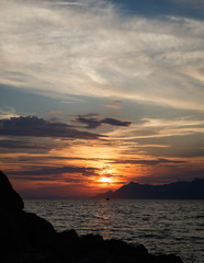 Sun goes down over the horizon.Adriatic Seaside under the cloudy sky.Beautiful sunset view.Far away...