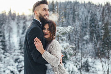 Bearded man and his lovely bride pose on the snow in a magic winter forest