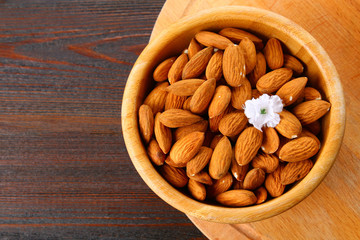 Raw dry nuts of almonds in a wooden bowl on a wooden table.