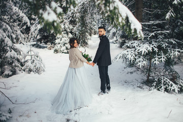 Bearded man and his lovely bride pose on the snow in a magic winter forest