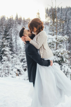 Bearded man and his lovely bride pose on the snow in a magic winter forest