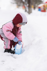 Fototapeta na wymiar kid puts a bucket in the snow in the park