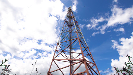 Cell phone tower against a blue sky. Tower of communications with a lot of different antennas under blue sky and clouds. Telecommunication tower with blue sky.