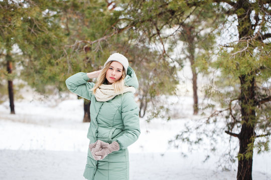 Young beautiful slender blonde girl outdoors in winter looking away. Portrait of an attractive model on a winter background. Space for text.