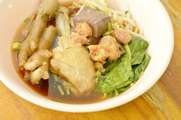 boiled chicken leg and feet with bean sprout in herb brown soup on bowl