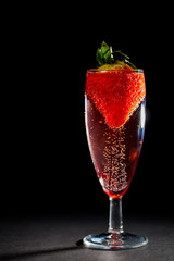 Celebration drink. Bubbly pink champagne glass with strawberry.