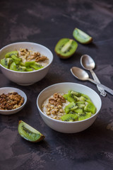 Oatmeal with kiwi fruit and walnuts. Two bowls porridge