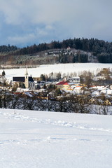 Catholic Church of the Birth of Virgin Mary in Milicin with Calvary on hill in snowy winter country in sunny day, Czech Republic