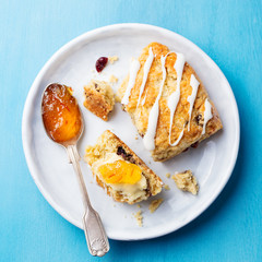 Scone with jam and butter on plate. Top view.