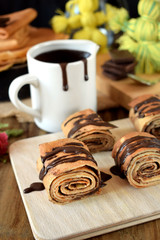 Crepes rolls with chocolate sauce on a wooden board