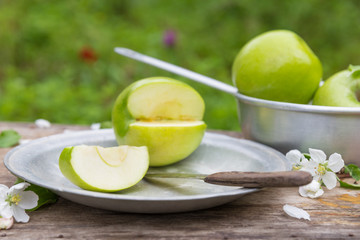 green apples with flowers on a wooden background