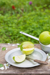 green apples with flowers on a wooden background