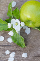 green apples with flowers on a wooden background