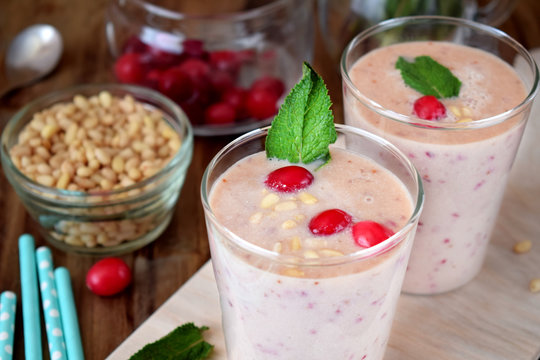 Protein cocktail for healthy nutrition decorated with cranberries, mint and pine kernel nuts in a glass