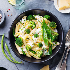 Pasta with green vegetables, creamy sauce in bowl