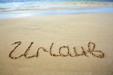 Word Vacation written on the sand near the sea.