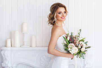 Portrait of a beautiful bride with a wedding bouquet. Blonde girl with curly hair and fashion makeup.