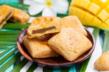 Mango cookies in wooden bowl with palm leaf.