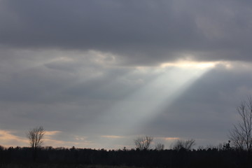 Obraz na płótnie Canvas Sun rays streaming though clouds on a cloudy, overcast morning.