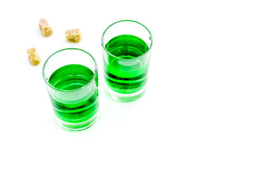 Absinthe shots near sugar cubes on white background top view copy space