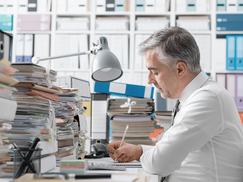 Businessman working in the office and piles of paperwork