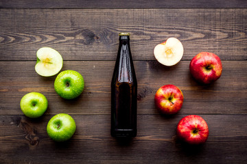 Apple cider. Low-alcoholic beveradge in dark bottle on dark wooden background top view