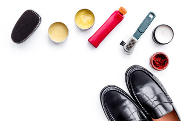 Shoe care products. Leather men shoes, shoe polish, brushes, wax on white background top view copy space