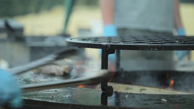 Chef pours oil on the surface of brazier and roasts steak of meat with rosemary on it