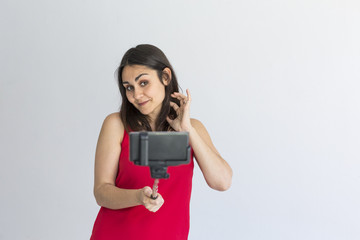 Happy beautiful woman taking a selfie with smart phone over white background. Lifestyle. Wearing casual clothing and smiling. Portrait Indoors