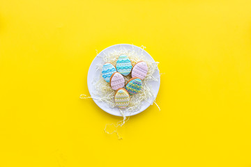 Easter gingerbread and cookies in shape of Easter eggs. Yellow background top view copy space