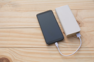 Mobile smart phones charging with power bank on desk and copy space.