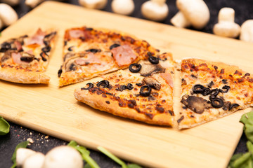 Four sliced of pizza on wooden board on a dark wooden table